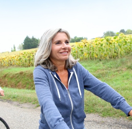 Smiling woman riding her bike near field of sunflowers