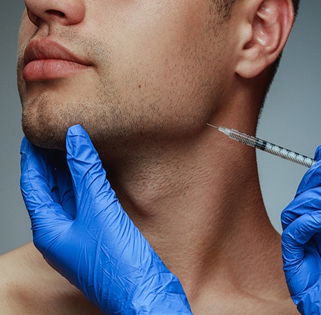 Gloved hand inserting BOTOX in Rock Hill into a male patient’s jaw