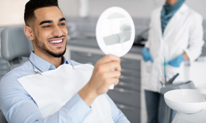 Man smiling at reflection in mirror in treatment chair