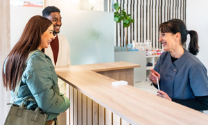 Dental receptionist talking to smiling couple