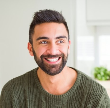 Young man in dark green sweater smiling