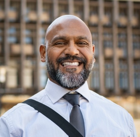 Man in tie smiling with bag over his shoulder