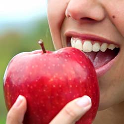 person biting into a red apple