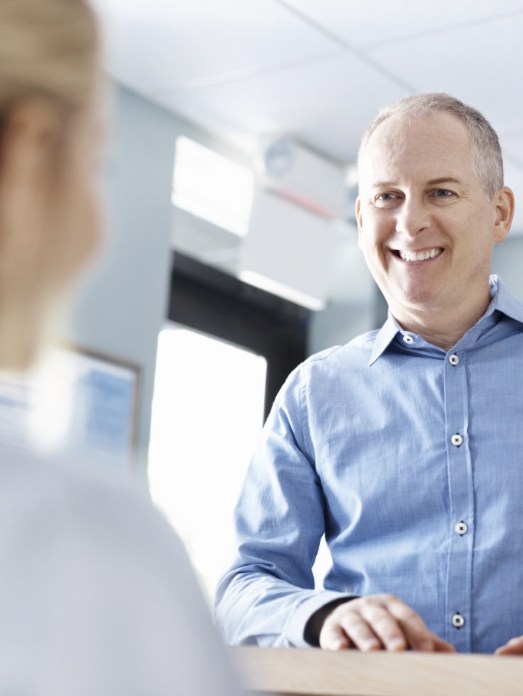 Man smiling at dental office receptionist