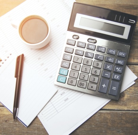 Calculator on desk next to papers and pen