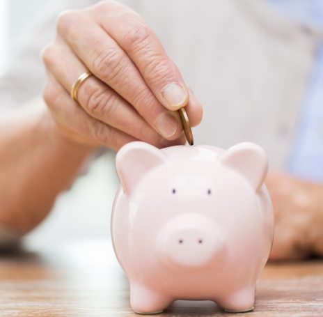 Person placing a coin in a pink piggy bank