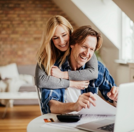 Woman and man hugging while looking at laptop