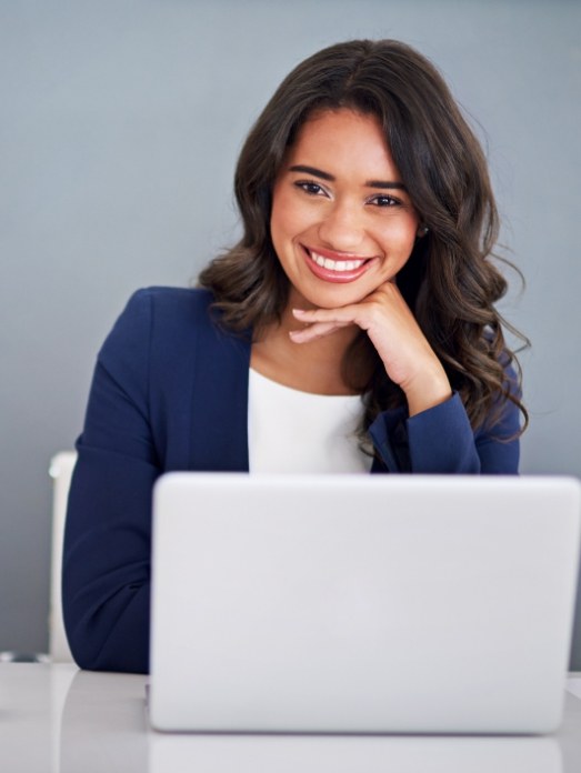 Woman smiling with laptop looking at dental special offers in Rock Hill