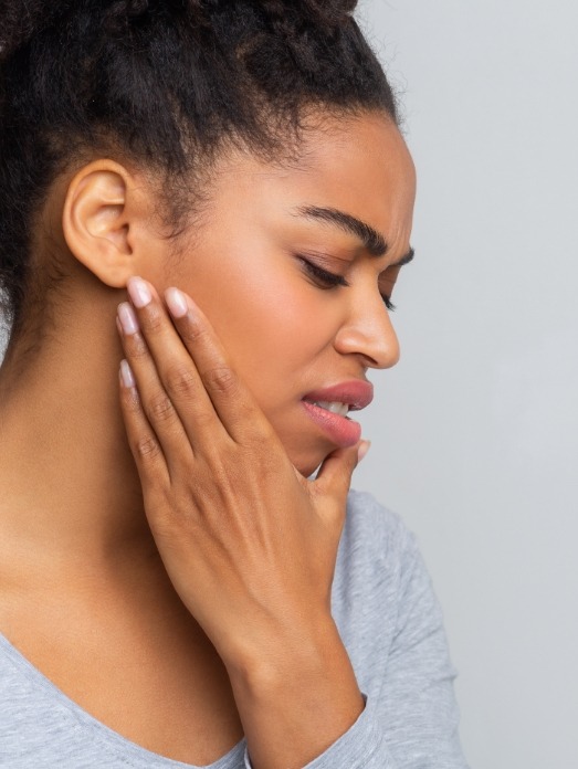 Wincing woman holding her jaw before T M J treatment in Rock Hill