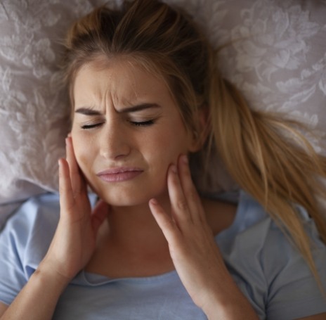 Woman rubbing her jaw in pain before TMJ therapy in Rock Hill, SC