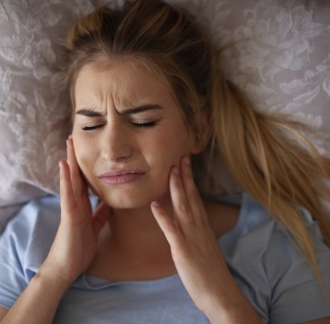 Woman wincing and holding both her jaw joints