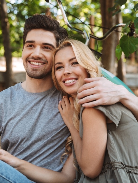 Young man and woman hugging outdoors and smiling with veneers in Rock Hill