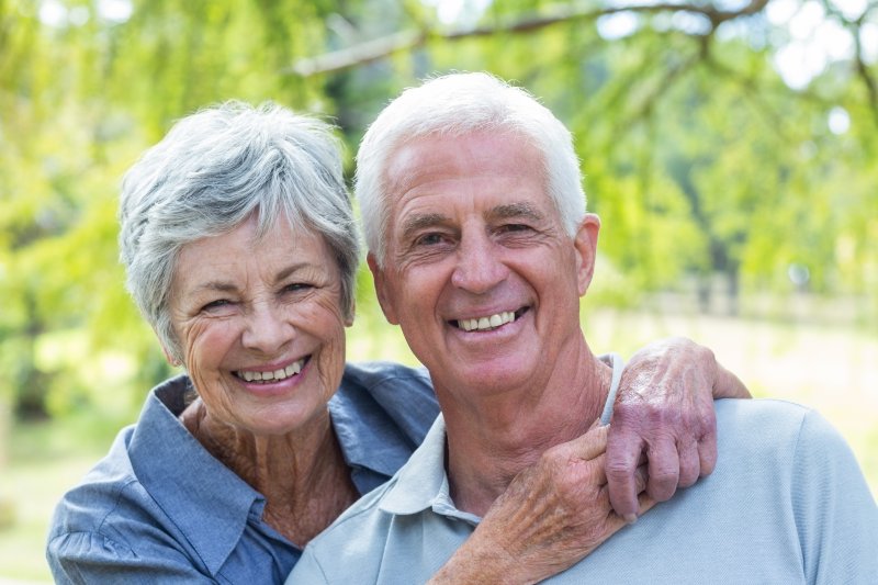 An older couple smiling after receiving implant-retained denture.