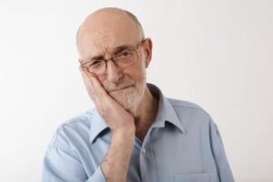 older man holding his face and looking concerned