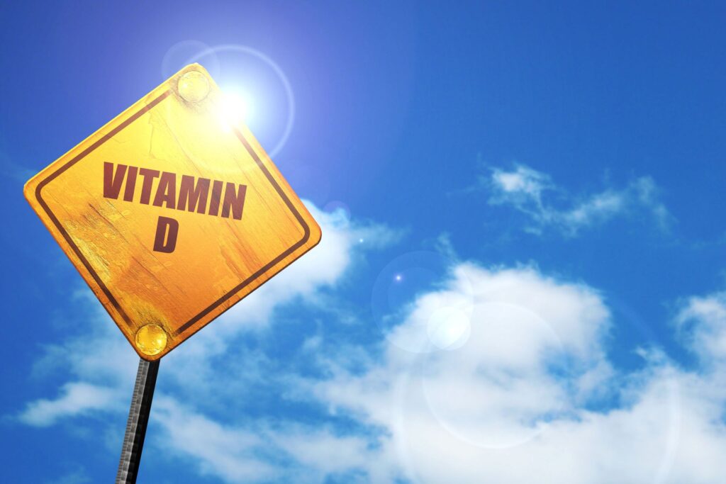 Yellow vitamin D sign against blue sky with white clouds
