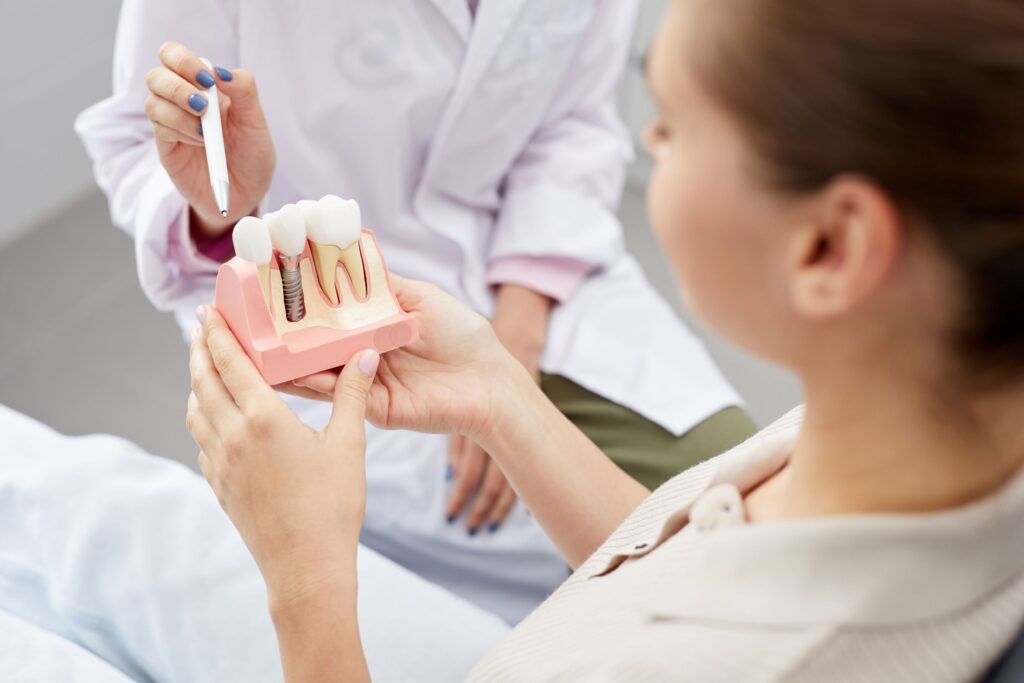 Patient holding sample dental implant with dentist pointing to it