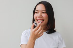 Woman smiling while putting on her retainer