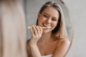 Young woman brushing teeth in front of mirror
